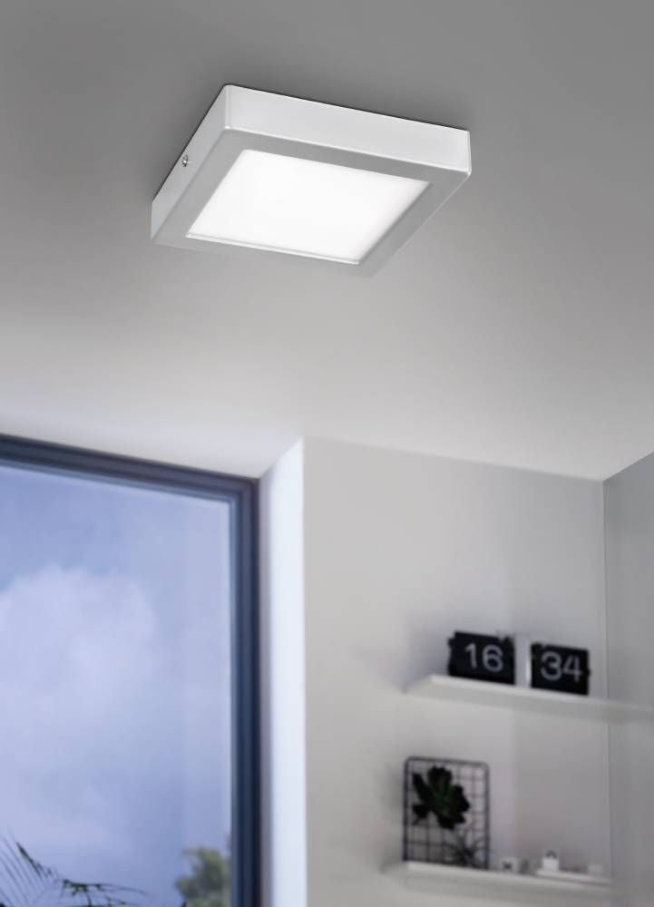 Luminaire installé au plafond dans une pièce claire, près d'une fenêtre et d'étagères.