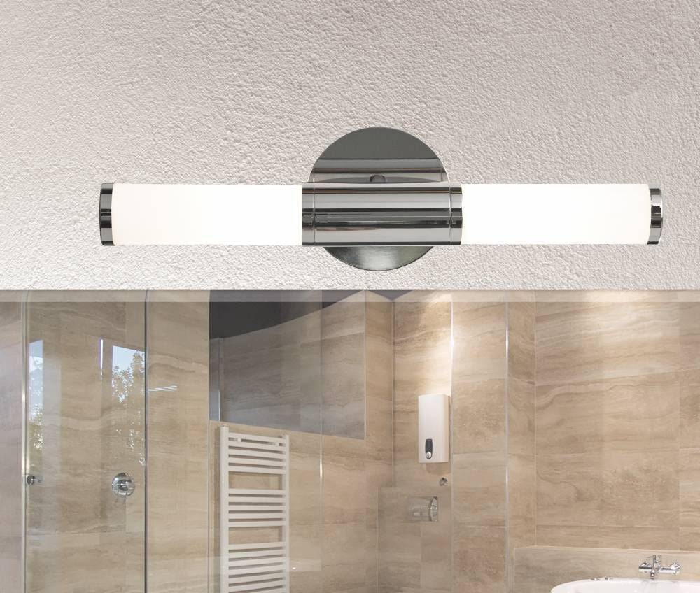 Applique murale chromée horizontale sur mur crépis, au-dessus d'une salle de bain beige