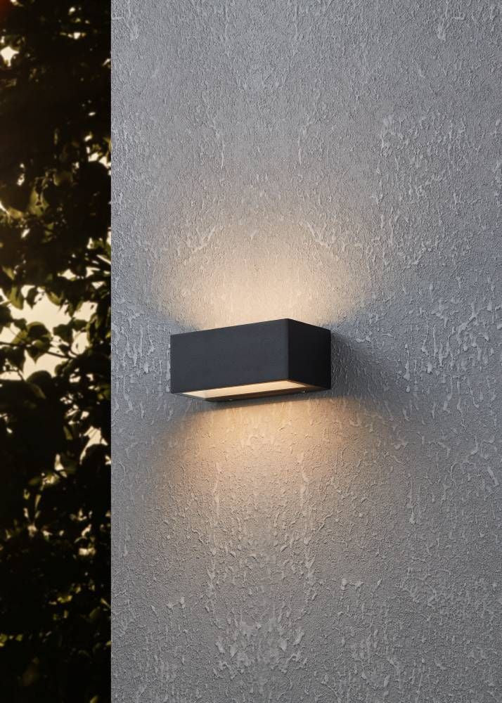 Applique noire installée sur un mur extérieur, éclairant vers le haut et le bas.