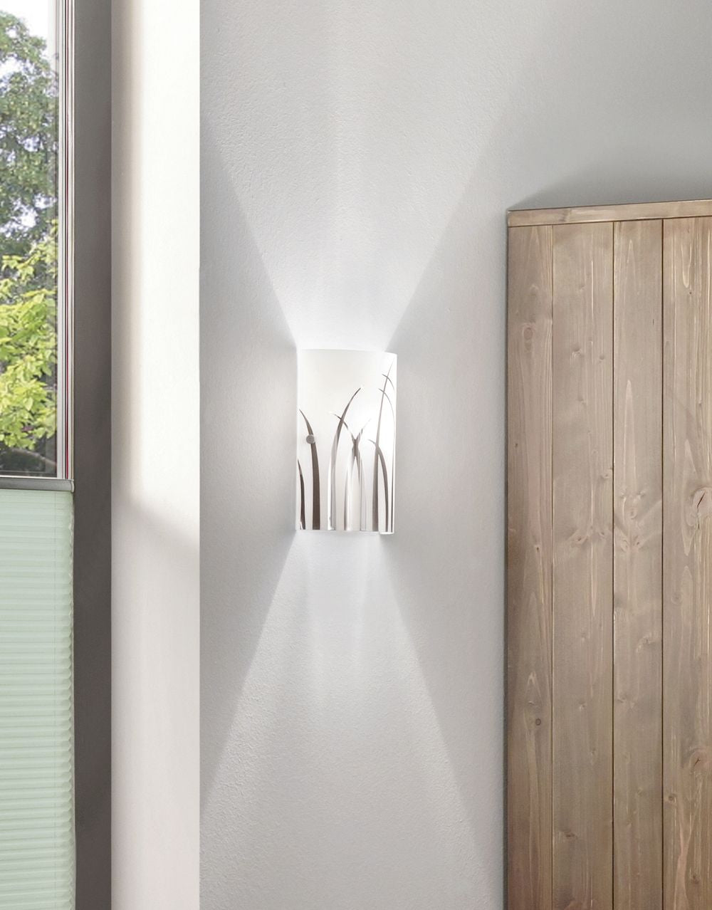 Applique murale allumée fixée sur un mur blanc, près d'une fenêtre et d'un meuble.
