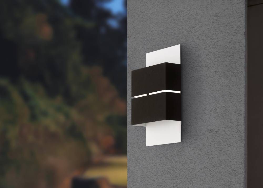 Applique murale noire et blanche installée sur un mur gris, arrière-plan extérieur flou