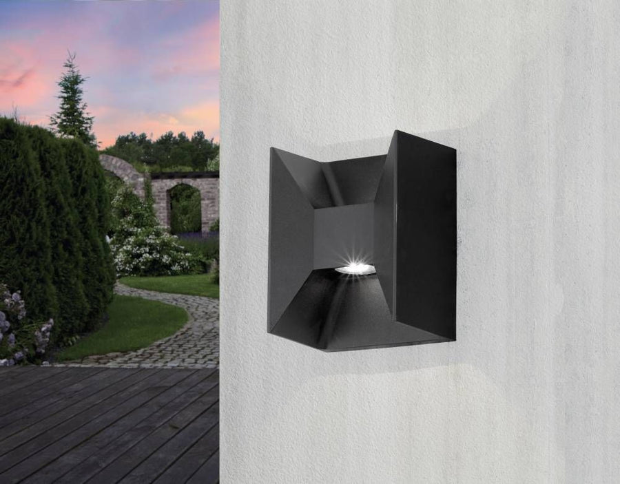 Luminaire extérieur fixé sur mur blanc clair, jardin paysager et ciel rosé