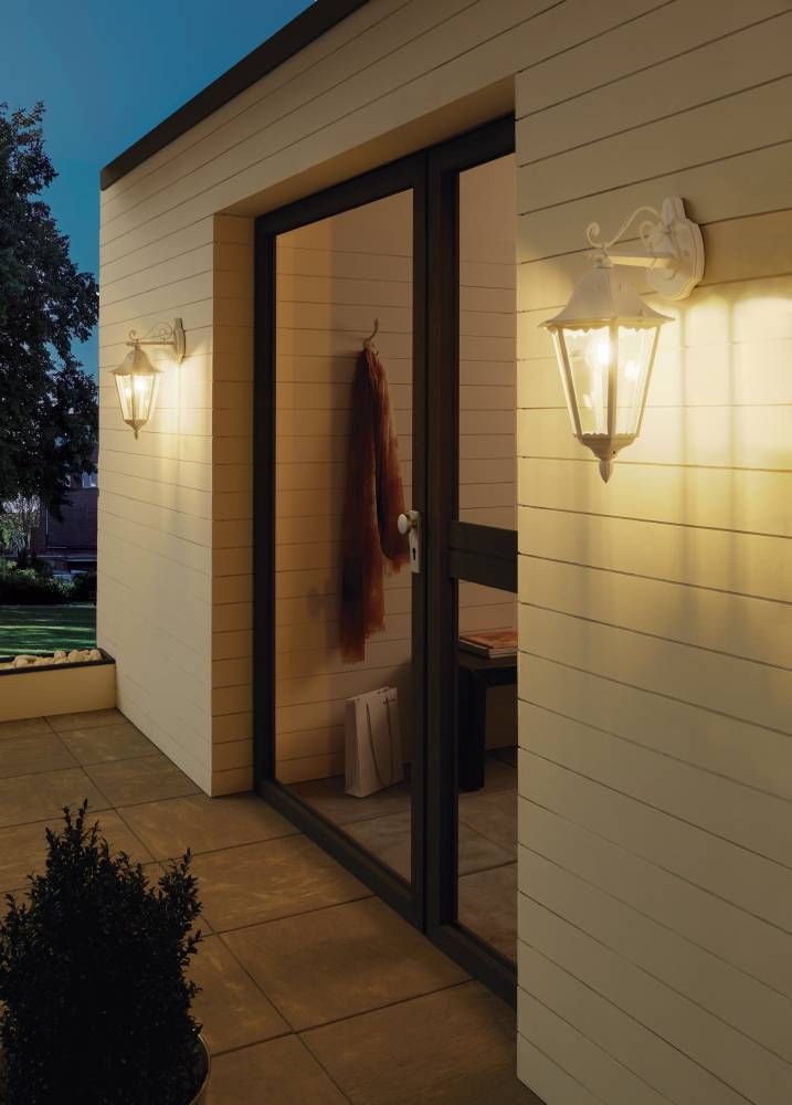 Mise en ambiance nocturne, deux appliques allumées éclairant une façade et une baie vitrée