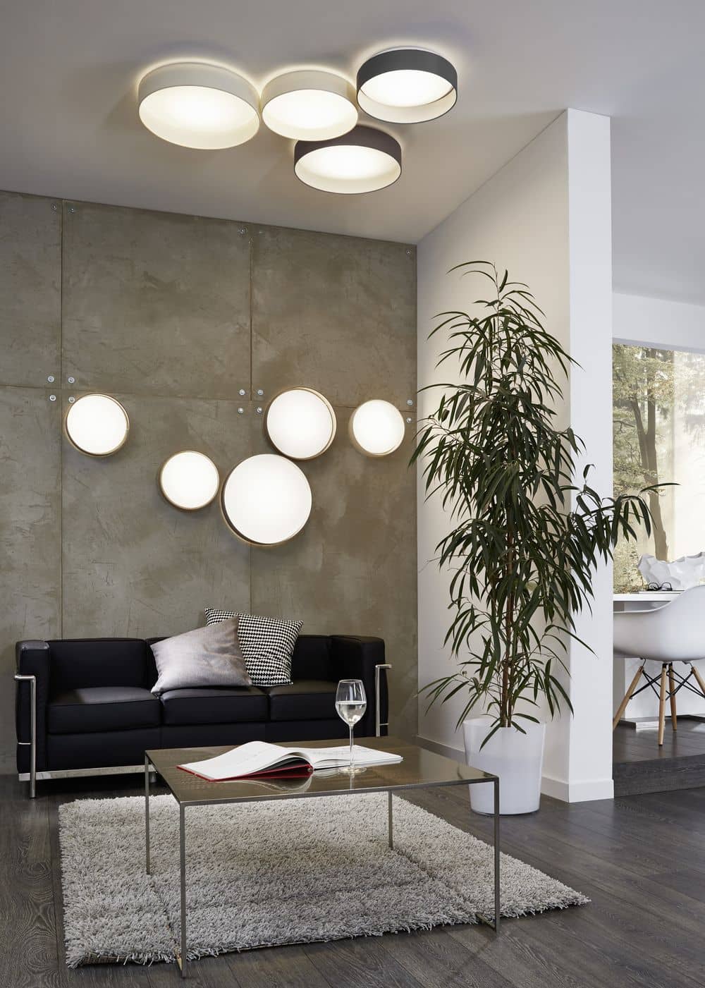 Mise en ambiance avec plusieurs plafonniers ronds allumés au plafond d'un salon.
