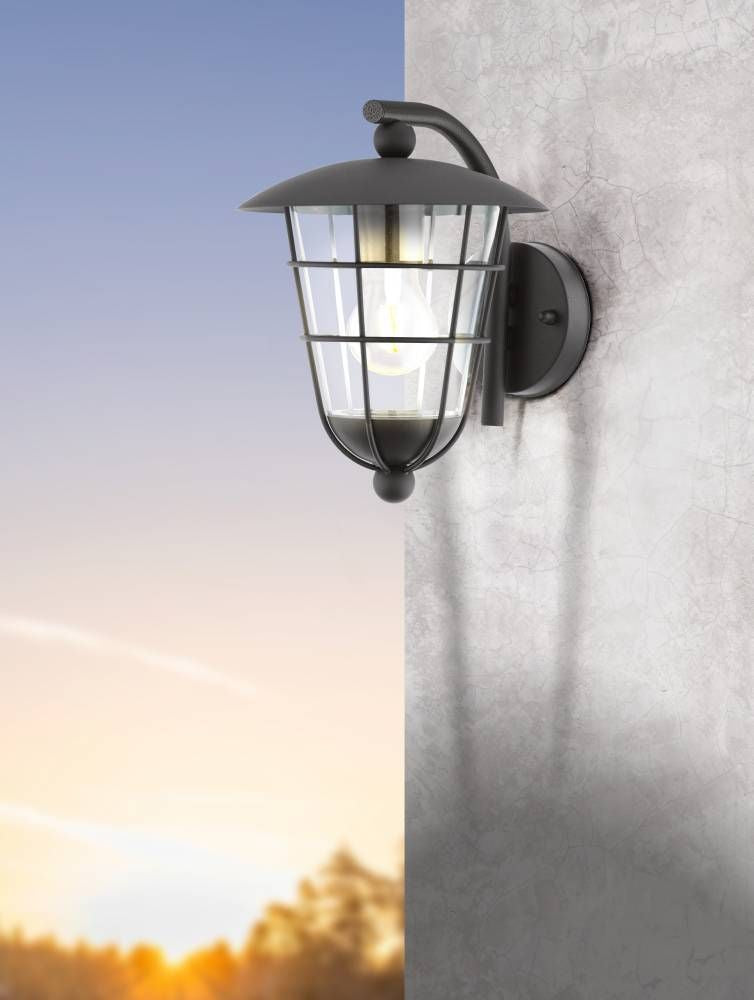 Mise en ambiance de l'applique extérieure noire fixée sur un mur au coucher du soleil.