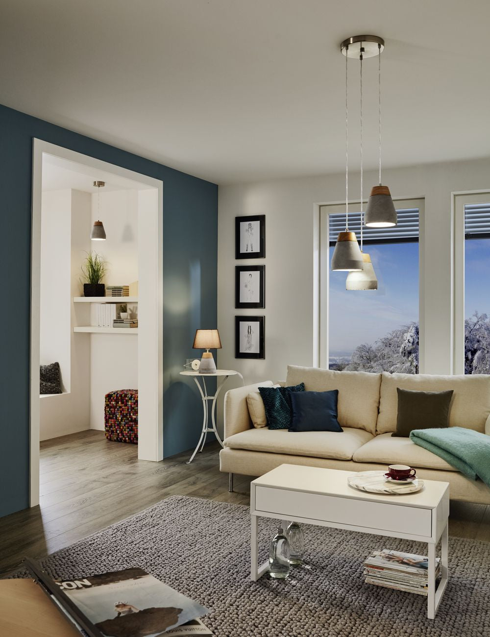 Mise en ambiance du salon avec la suspension allumée au-dessus du canapé beige