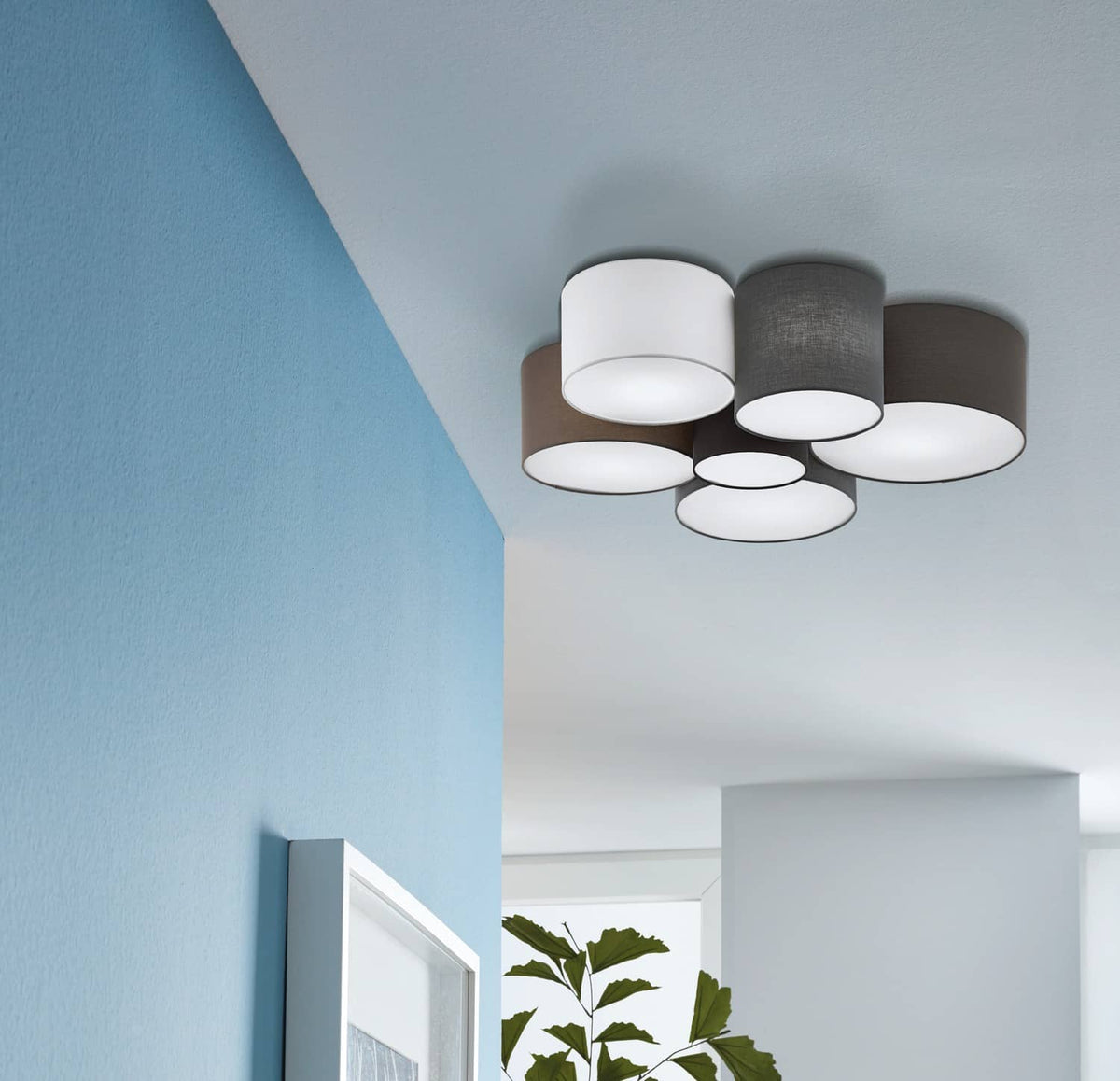 Luminaire installé au plafond dans un intérieur bleu clair avec cadre et plante verte