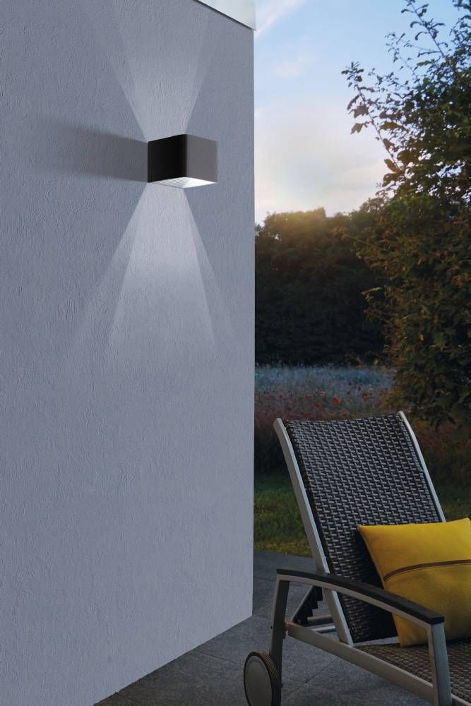 Applique murale noire installée sur mur extérieur, éclairage haut et bas, jardin et chaise longue