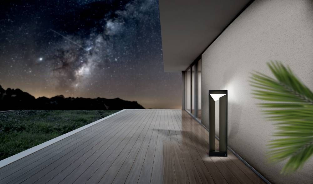 Mise en ambiance nocturne, ciel étoilé et terrasse en bois, lampadaire allumé.