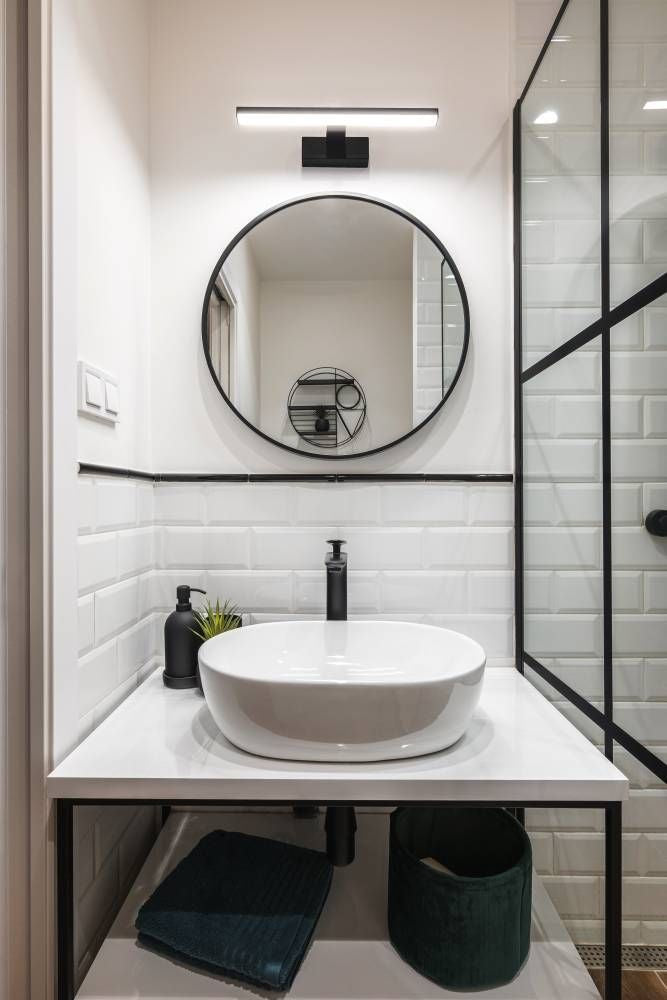 Luminaire installé au-dessus d'un miroir rond dans une salle de bain moderne
