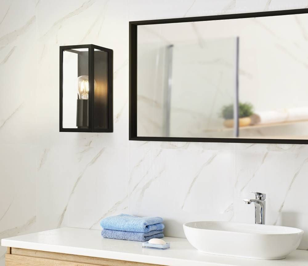 Applique murale noire allumée à côté miroir dans salle de bain marbre
