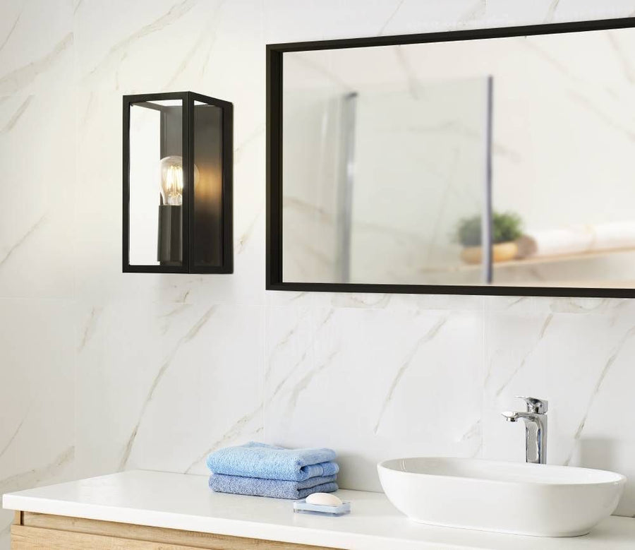 Applique murale noire allumée à côté miroir dans salle de bain marbre
