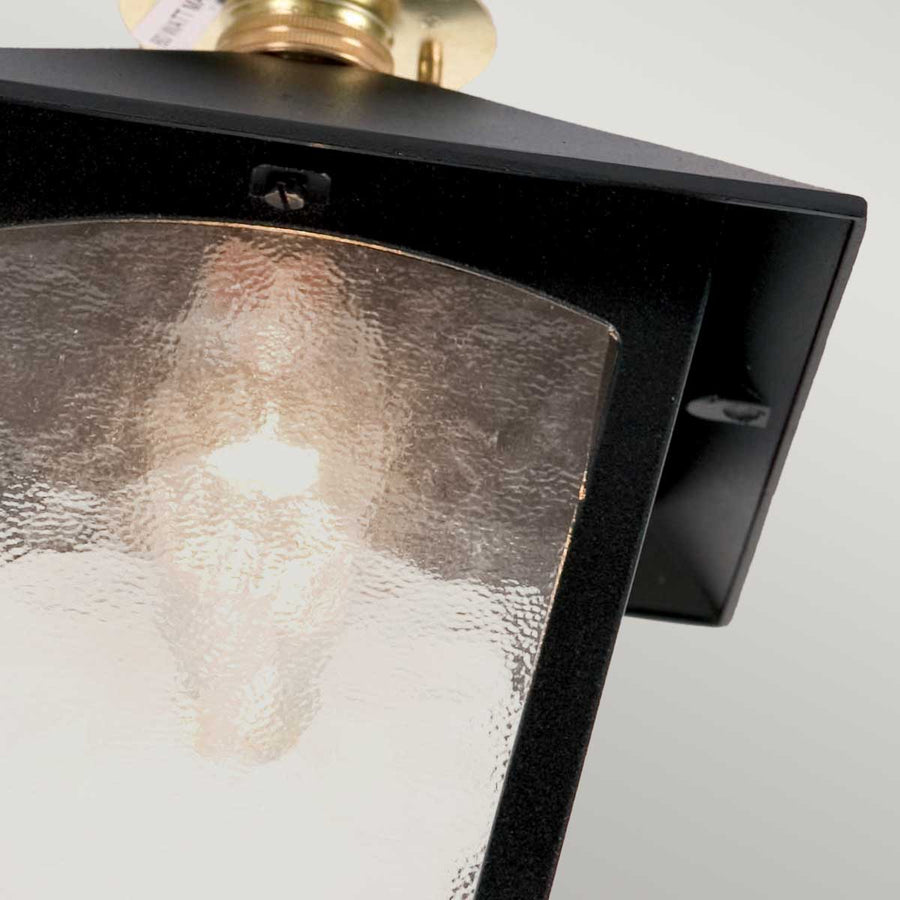 Détail du cadre noir laqué et du verre martelé éclairé par l'ampoule.