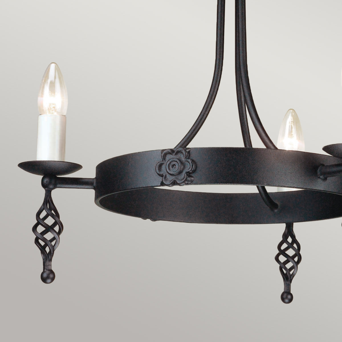 Gros plan sur l’anneau noir, fleur décorative et bras porte-bougies.