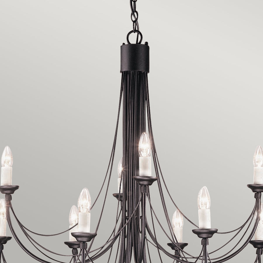 Détail du haut du lustre : chaîne, corps central noir et premières ampoules allumées.