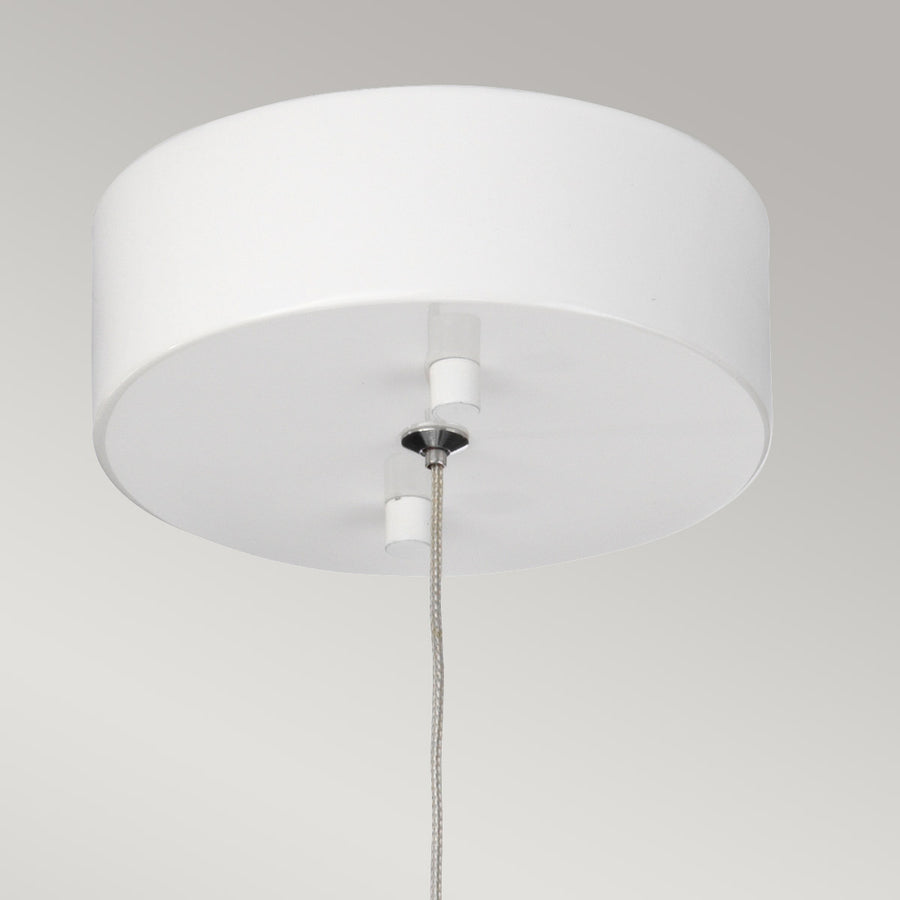 Gros plan sur la rosace blanche fixée au plafond et le câble tressé.