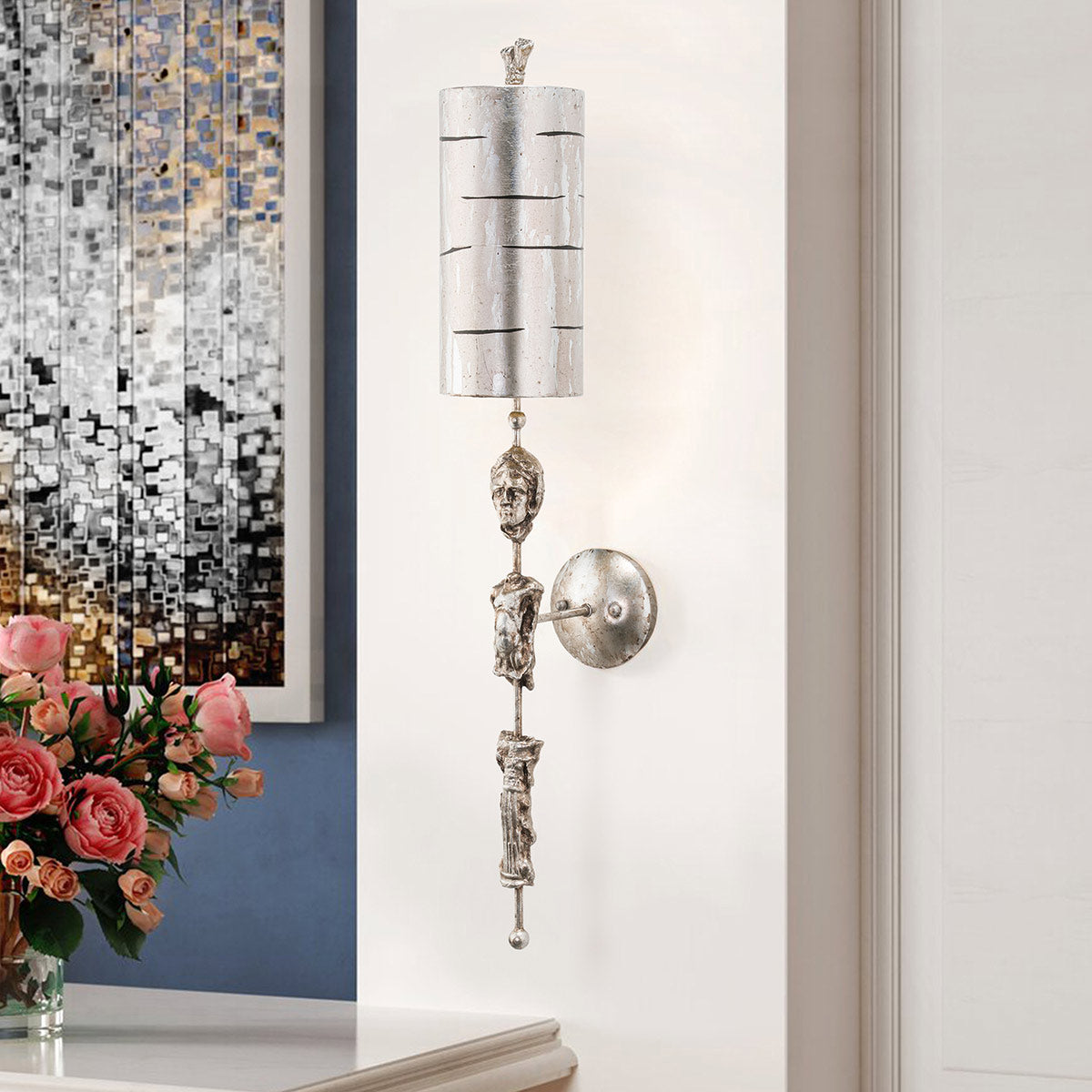 Mise en ambiance de l'applique allumée sur un mur blanc près d'une mosaïque.