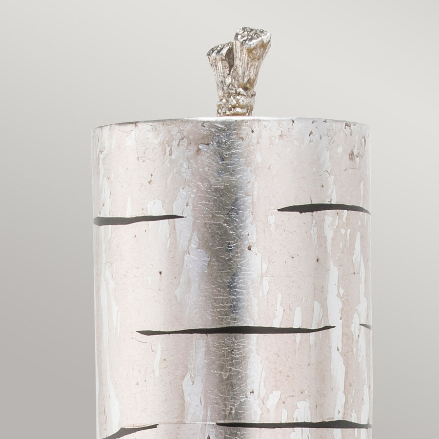 Détail du sommet de l'abat-jour cylindrique argenté et de son ornement sommital.