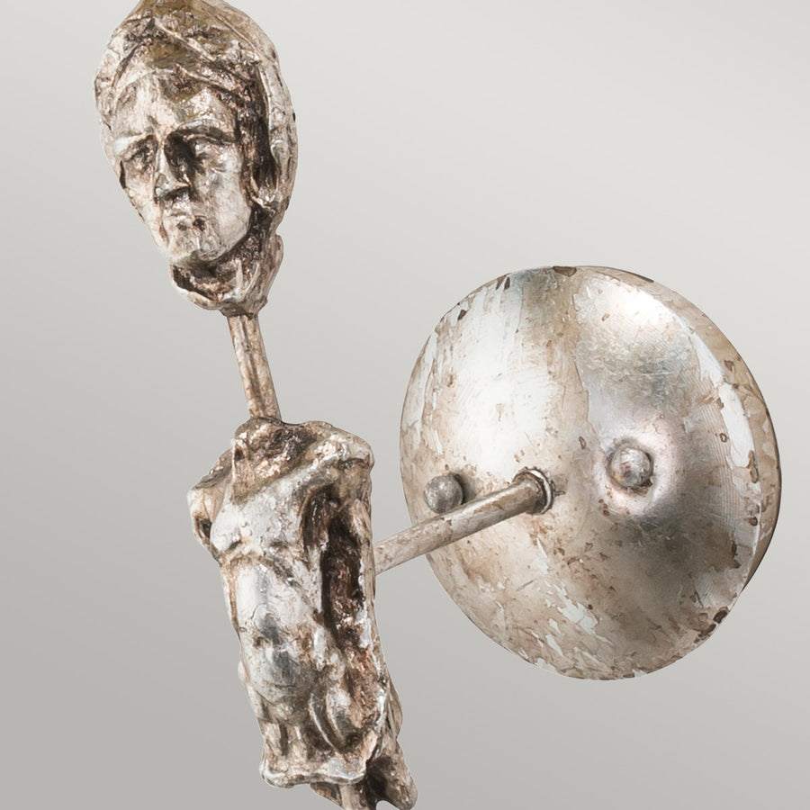 Détail de la platine murale ronde et du torse sculpté en métal argenté patiné.