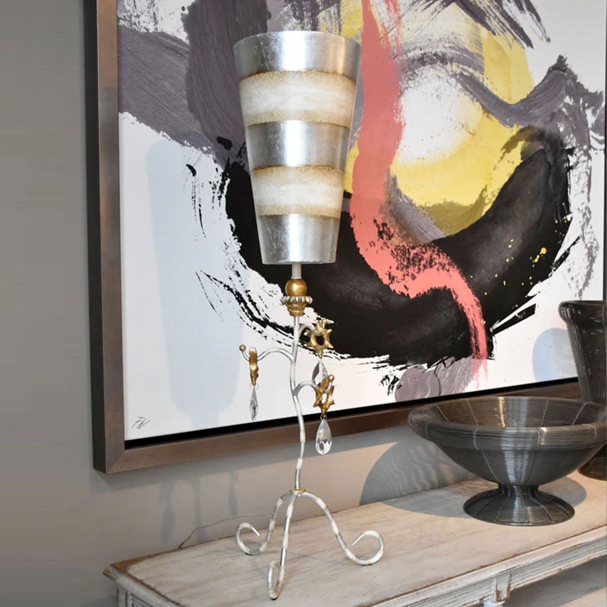 Lampe à poser sur console devant tableau abstrait coloré, intérieur décoratif.
