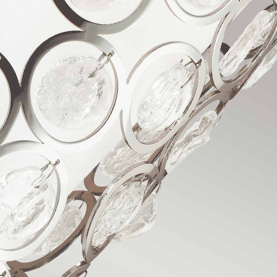 Détail des cercles nickelés et pastilles de verre coulé suspendues sur fond blanc
