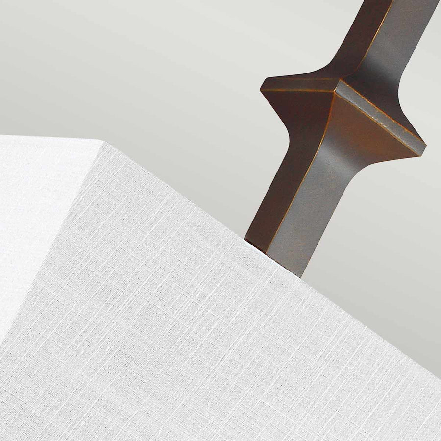 Détail du fût bronze brossé traversant l'abat-jour en tissu texturé clair