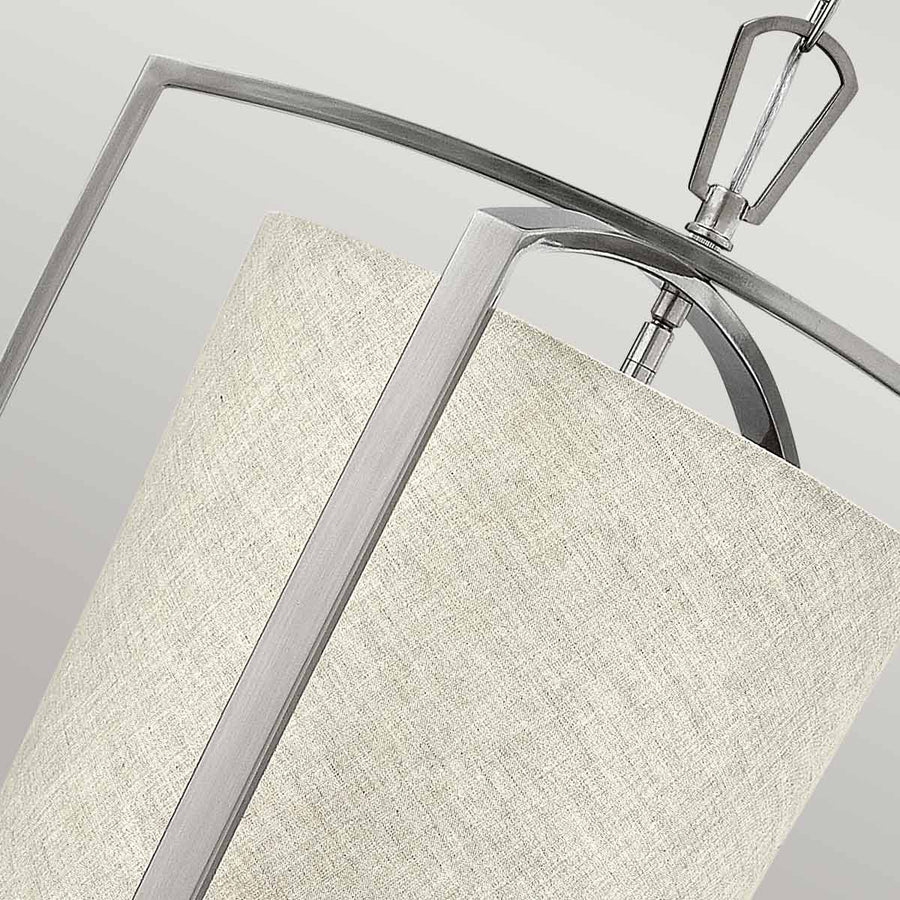 Détail du raccord supérieur entre le cadre métallique et l'abat-jour textile texturé beige.