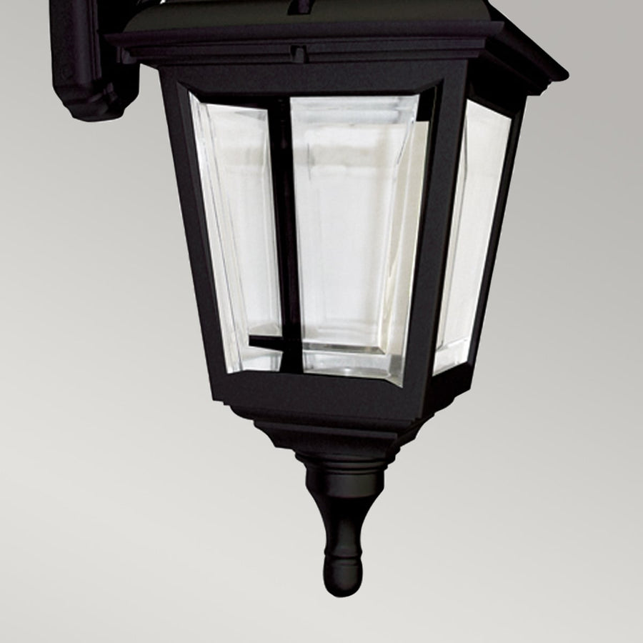 Détail du bas du luminaire avec panneaux de verre et finial noir
