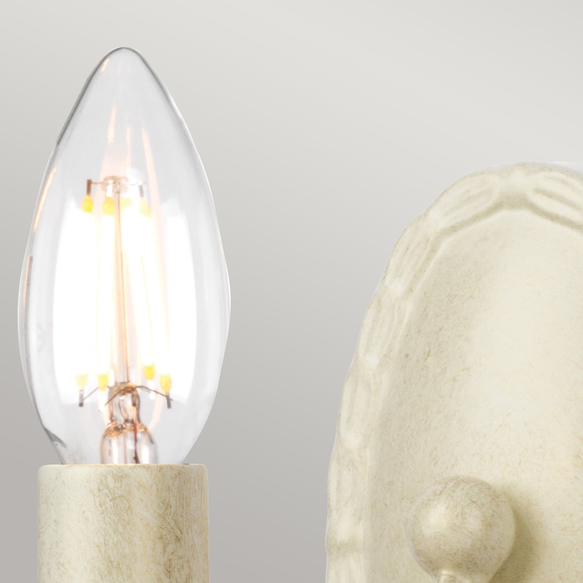 Détail de l'ampoule transparente allumée et de la douille crème