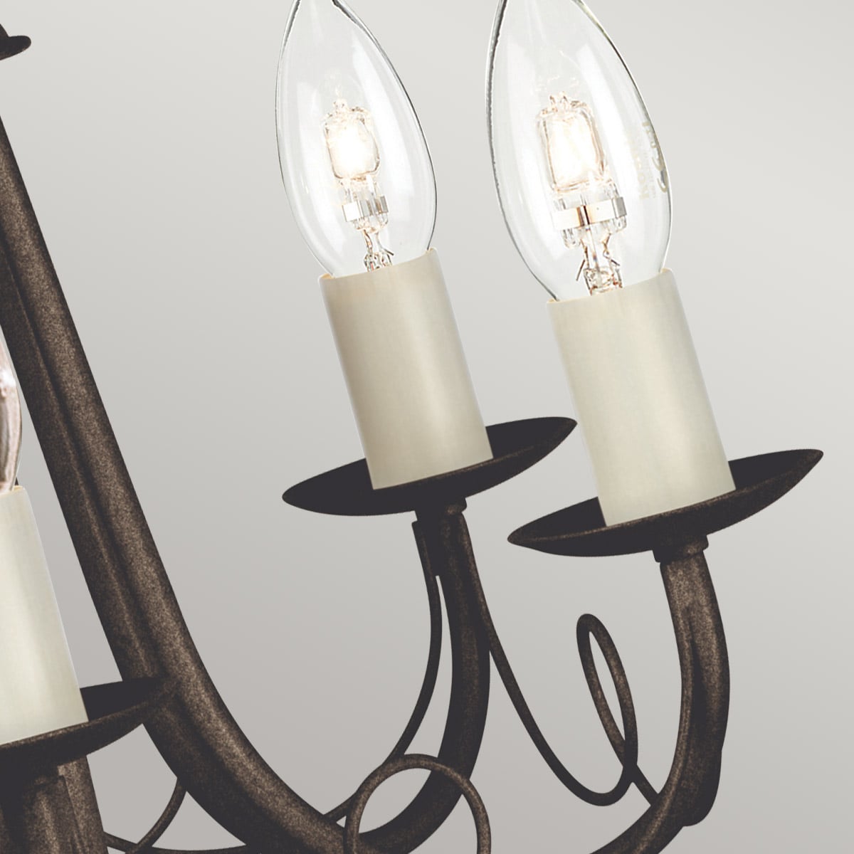 Détail de deux ampoules bougies et douilles ivoire sur le lustre noir et doré.