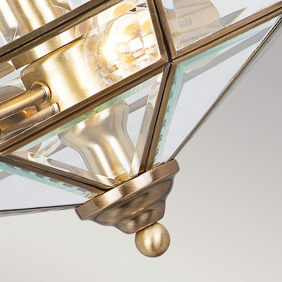 Gros plan sur la pointe en laiton et l'assemblage des panneaux de verre.