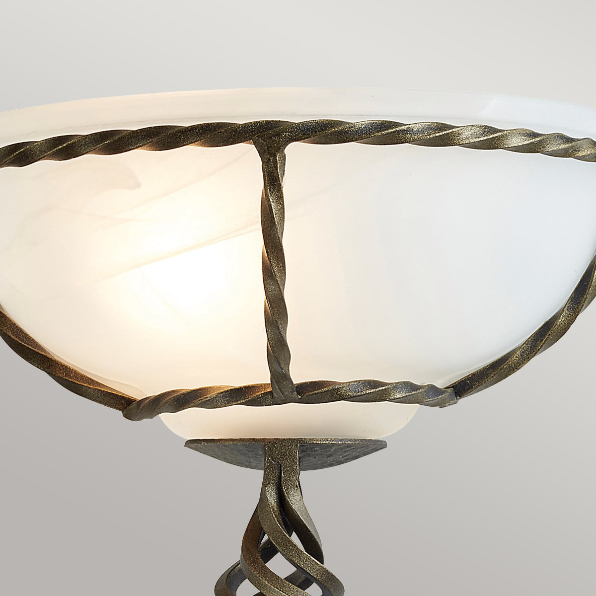 Détail du verre blanc maintenu par une cage métallique torsadée noire et dorée