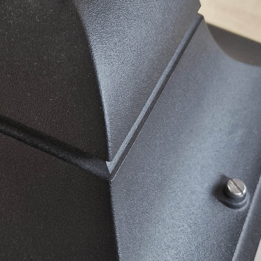Gros plan sur la texture métallique noire et la vis de fixation du sommet
