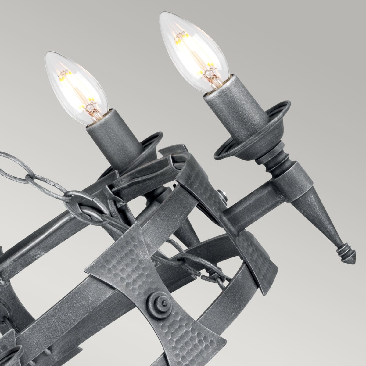 Vue rapprochée de deux ampoules bougies et des bras métalliques décorés du luminaire.