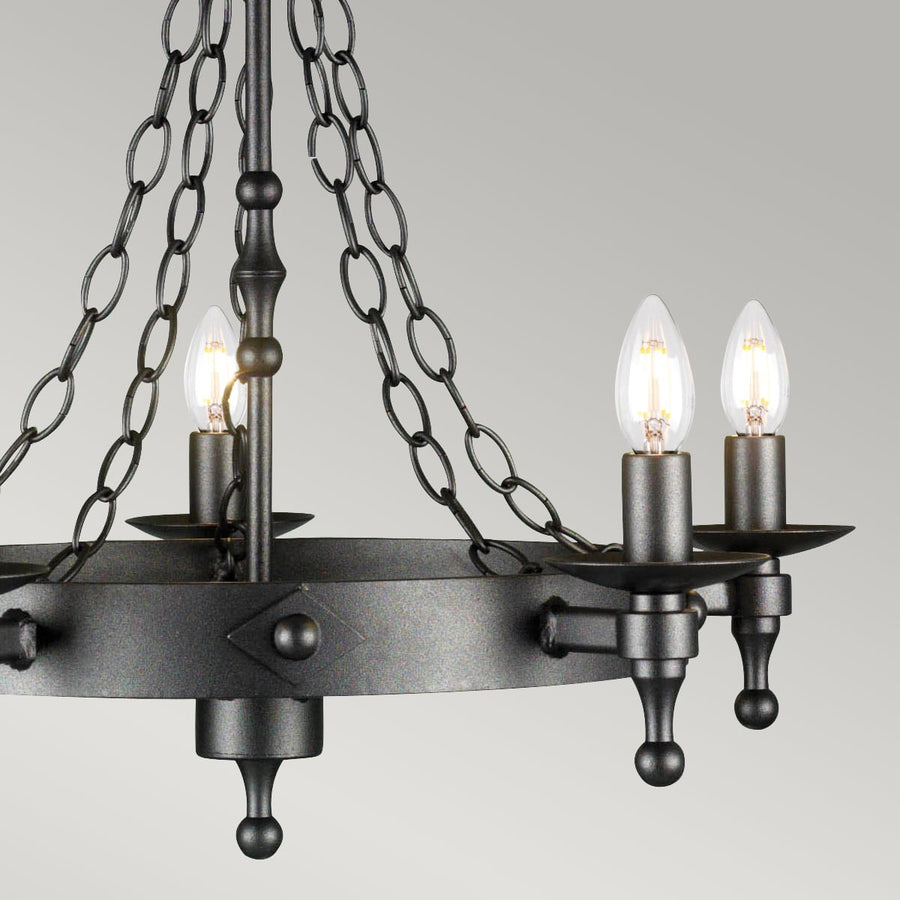 Gros plan sur le cercle central et les bras porte-bougies du luminaire en métal texturé.
