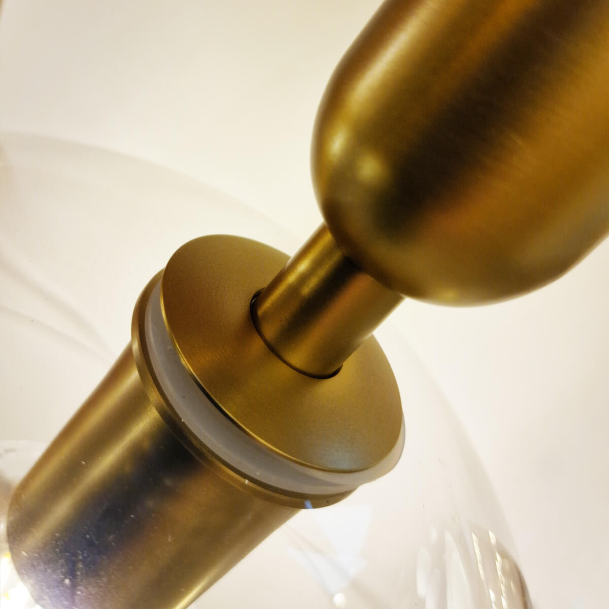 Détail rapproché de la fixation entre le verre transparent et la douille dorée