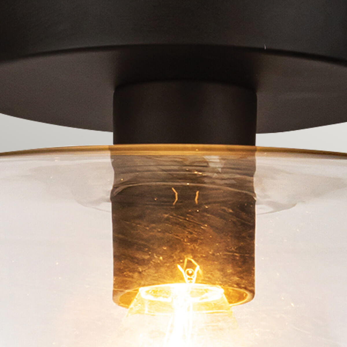 Gros plan sur la douille et l'ampoule dorée à travers le verre transparent
