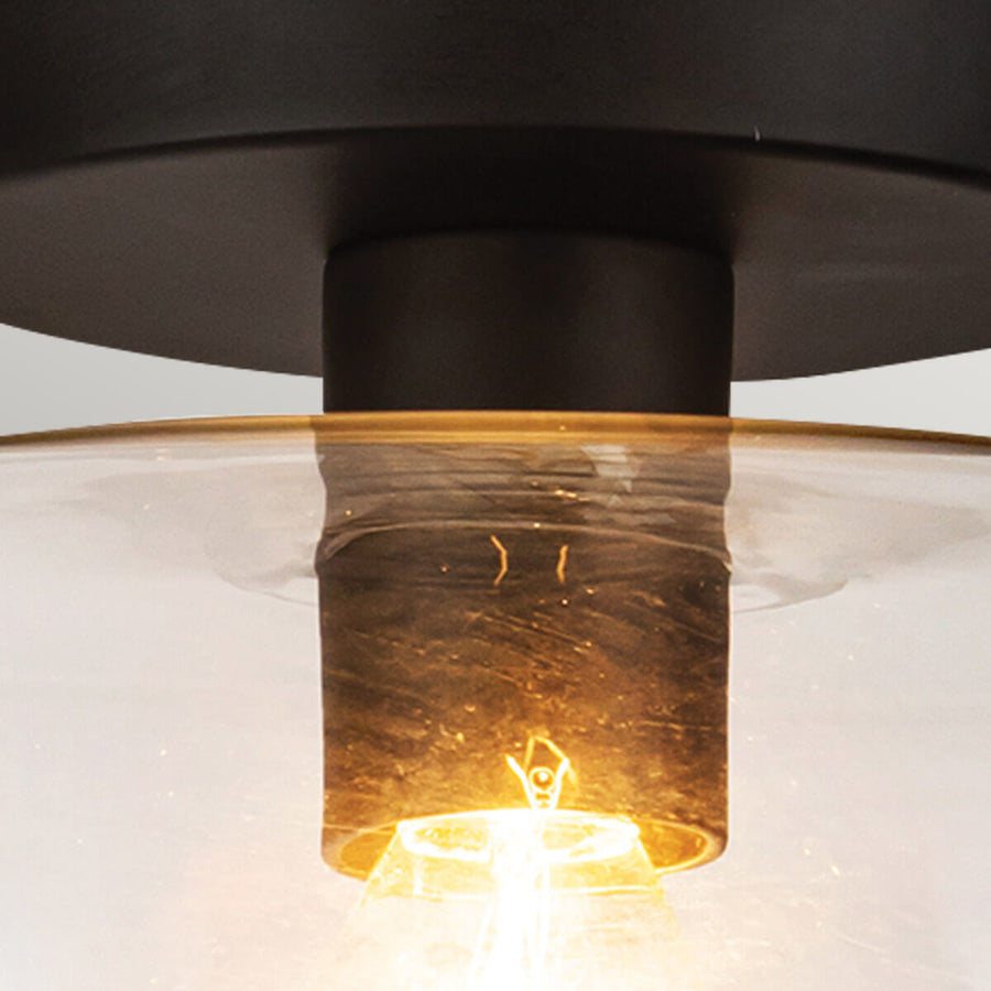 Gros plan sur la douille et l'ampoule dorée à travers le verre transparent