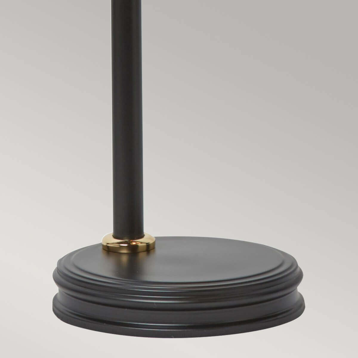 Détail de la base ronde noire avec bague dorée au pied