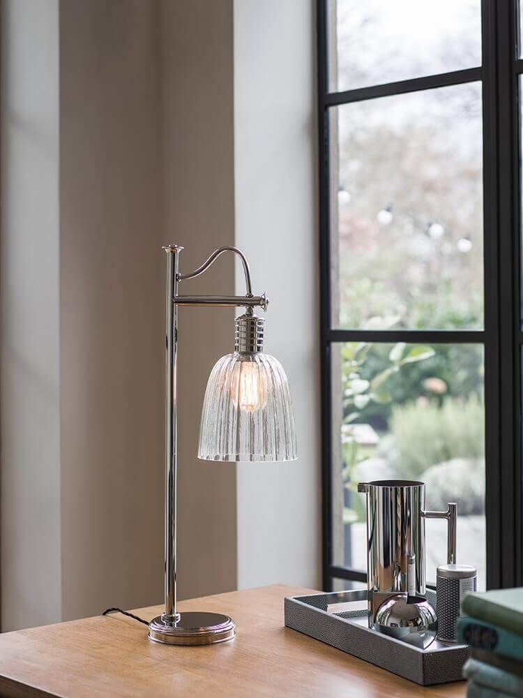 Même lampe avec abat-jour en verre strié, posée sur une table en bois.