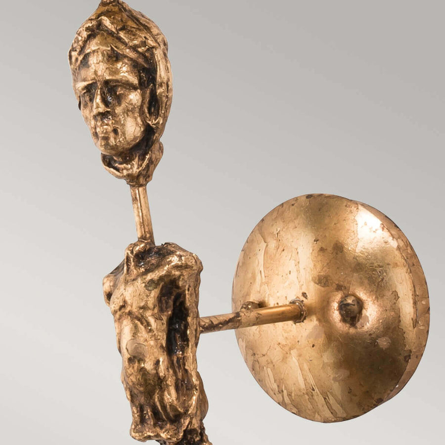 Détail de la platine murale ronde dorée et du visage sculpté antique