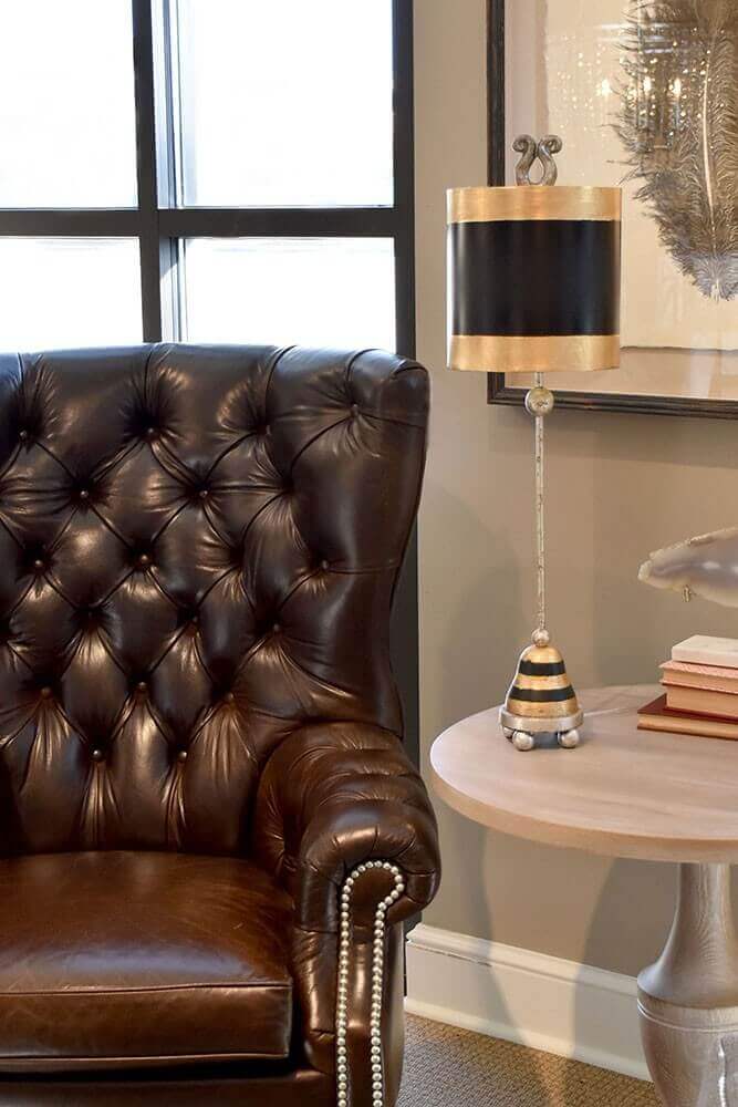 Mise en ambiance dans un salon, lampe posée sur table près d'un fauteuil en cuir.