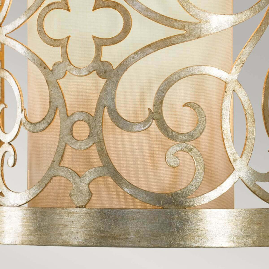 Gros plan du bas volutes métalliques et anneau central sur abat-jour beige.