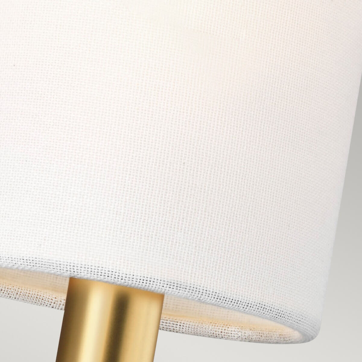 Gros plan sur la texture de l'abat-jour en tissu blanc et la douille en laiton