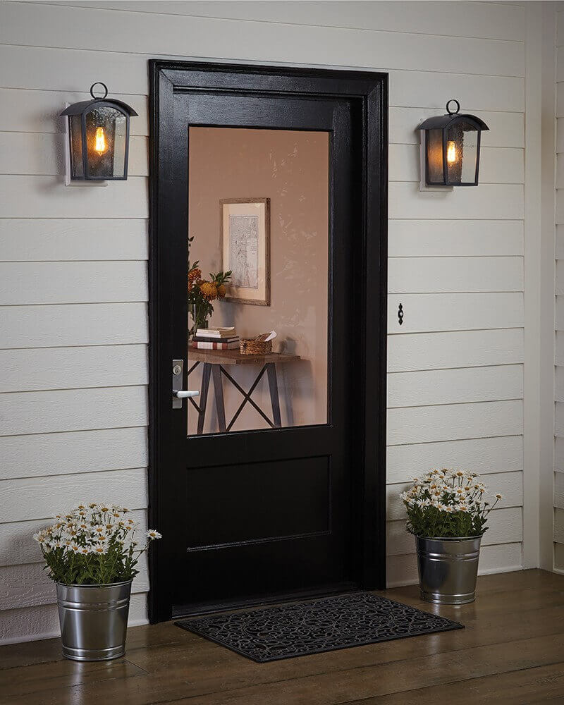 Mise en ambiance de deux appliques encadrant une porte noire sur une terrasse