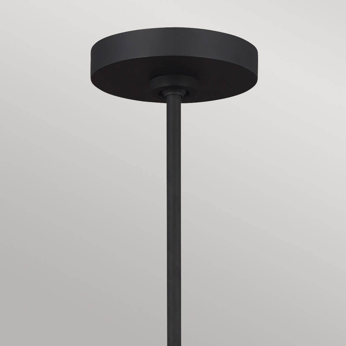 Détail de la rosace de plafond noire et de la tige de suspension verticale