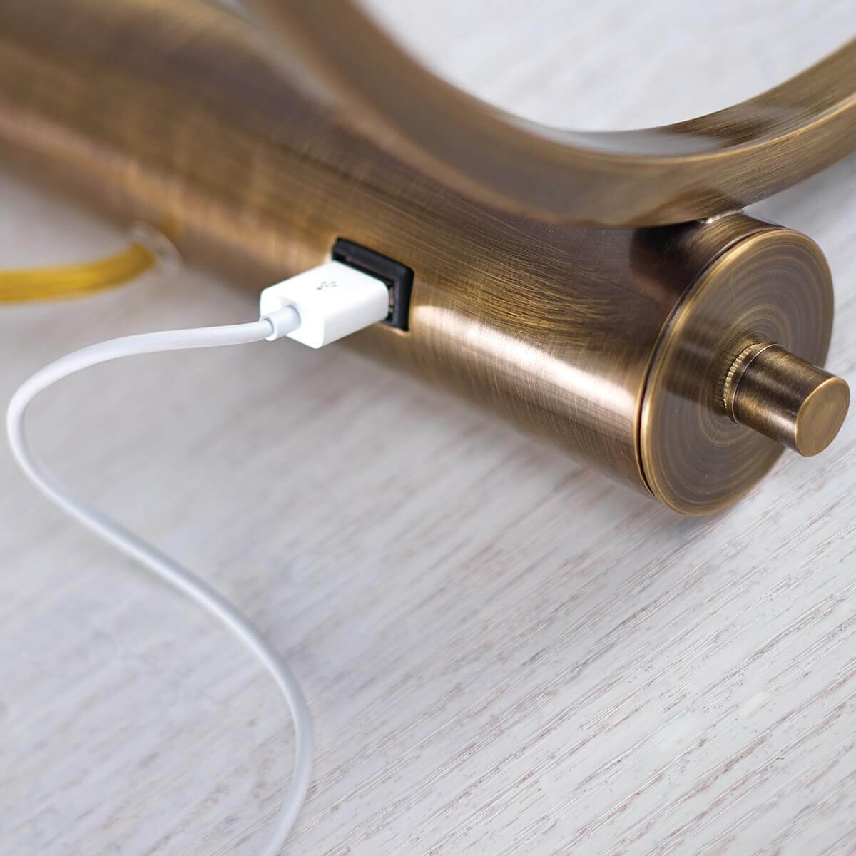 Détail du socle en métal brossé montrant le câble USB blanc branché sur la prise