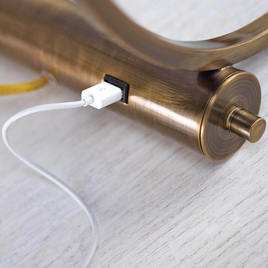 Détail du socle en métal brossé montrant le câble USB blanc branché sur la prise
