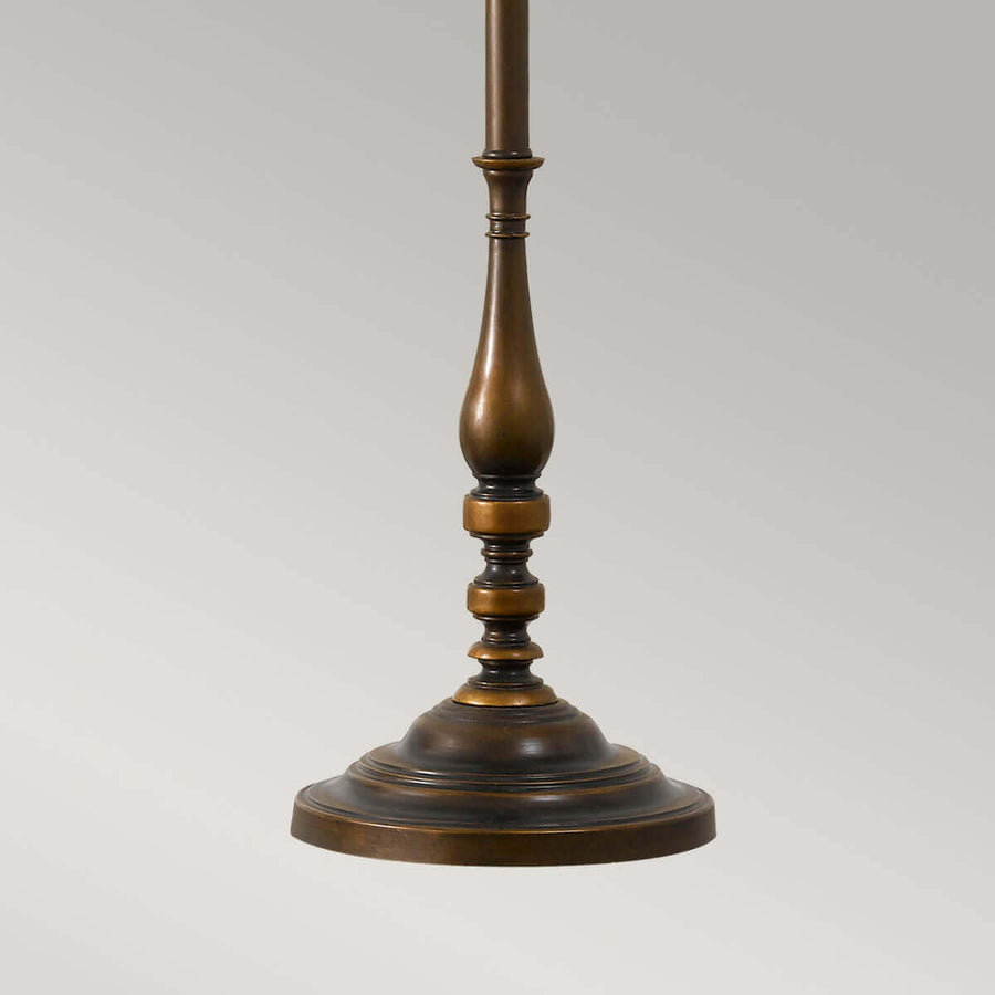 Détail de la base circulaire et du pied tourné en bronze foncé.