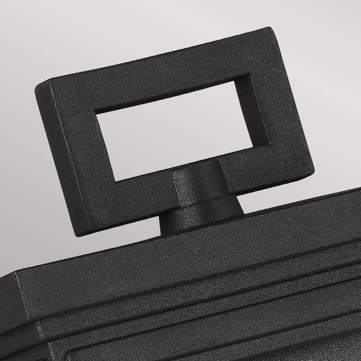 Détail du sommet de l'applique montrant l'anneau rectangulaire noir et sa fixation.
